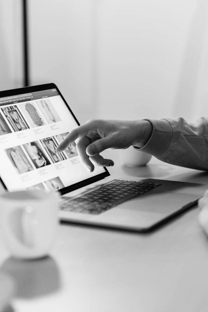 Black and white photo of a person shopping online on a laptop, highlighting e-commerce technology.