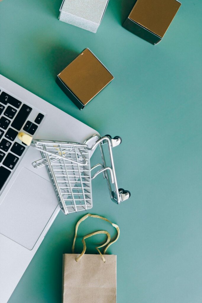 Flat lay of a laptop, shopping cart, and parcels symbolizing online shopping and ecommerce.