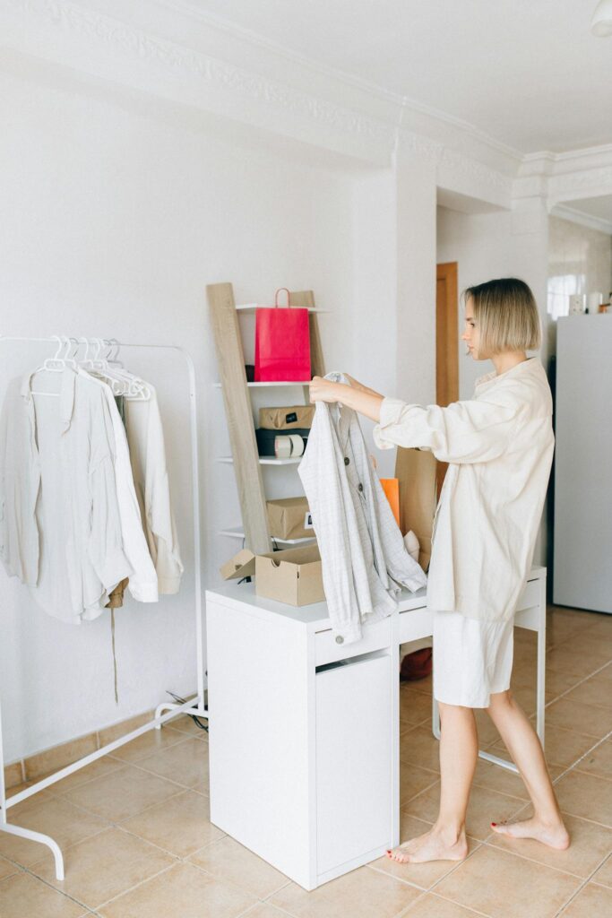 Woman sorting garments in a modern apartment, showcasing a clean, minimalist lifestyle.